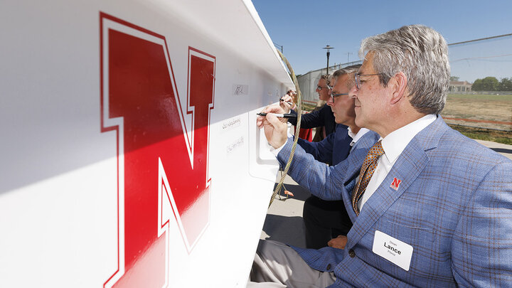 College of Engineering Dean Lance Pérez signs his name to the final beam alongside Chancellor Ronnie Green and other dignitaries at the Kiewit Hall topping off ceremony Aug. 31.