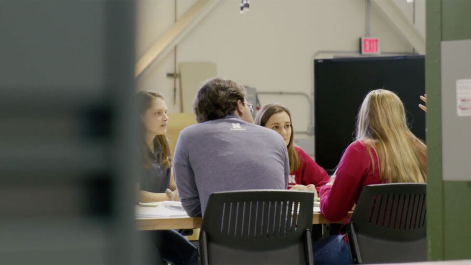 Students sitting around a table talking.