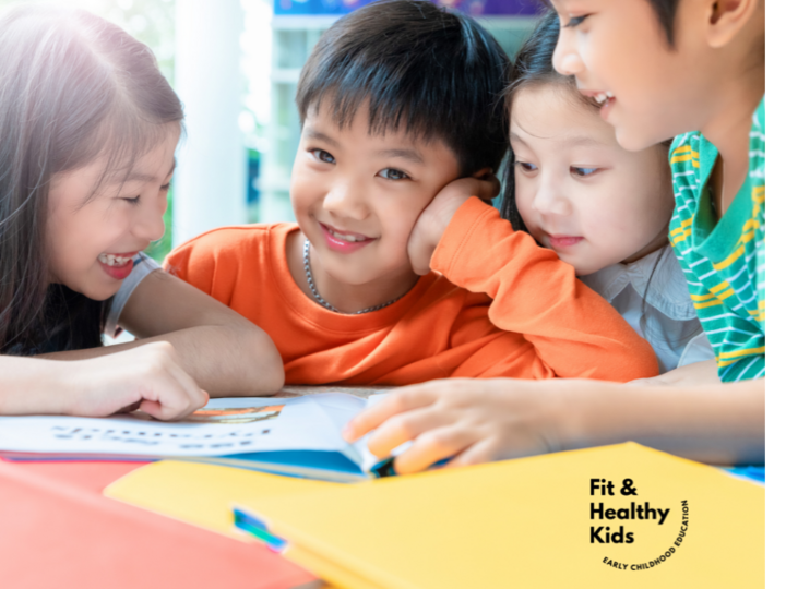 Four children reading book at the table