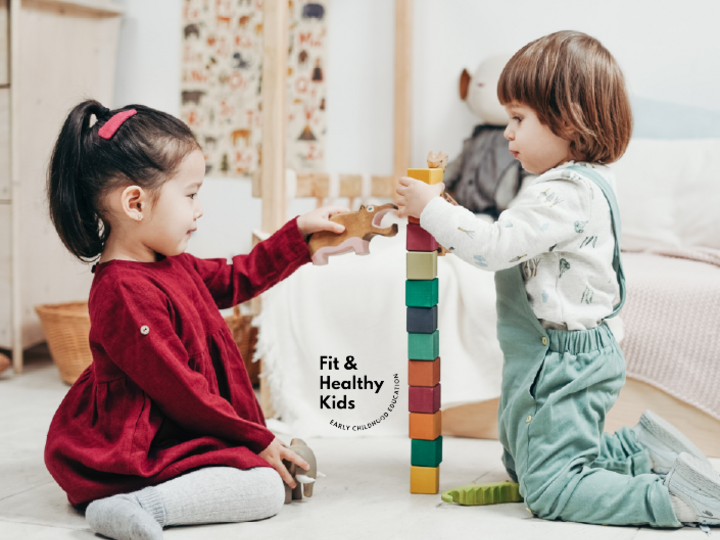 two young children stacking a tower of blocks together