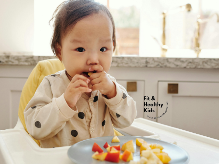 Infant eating fruits and vegetables in a high chair