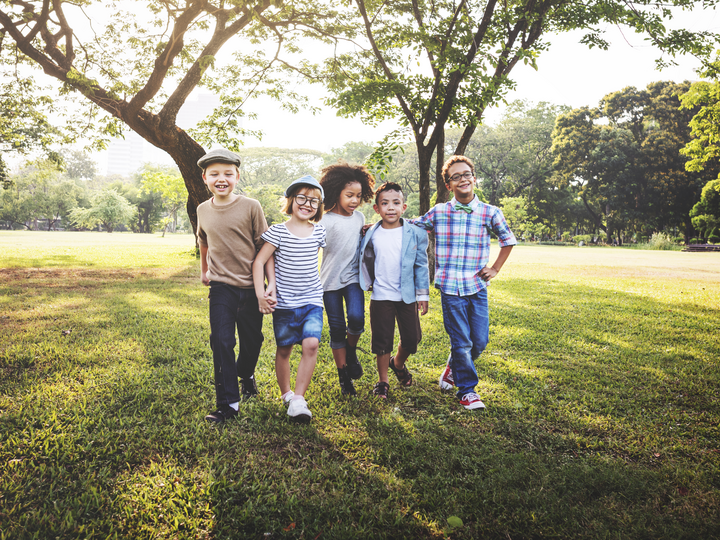 Five children walking in a park together.