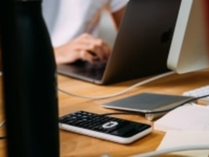 Computer on table with person working on records.