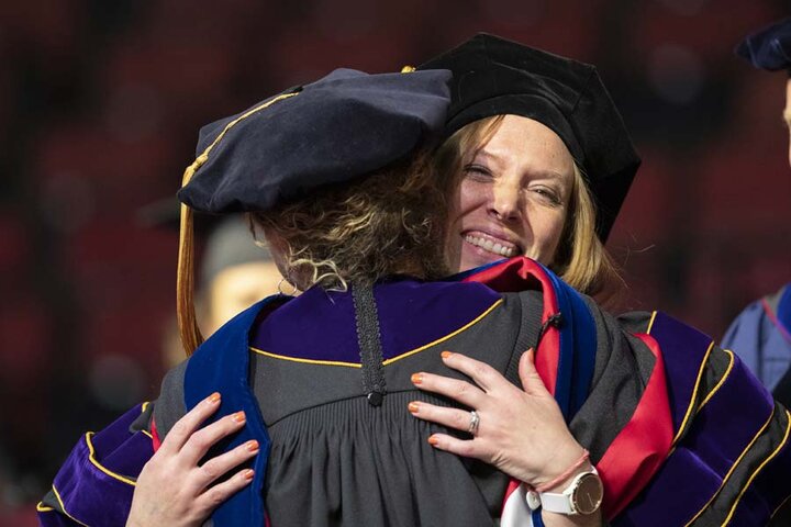 Ph.D Graduate Student hugging professor at graduation ceremony
